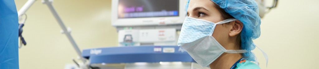 Nurse anesthesiologist in surgical room with scrubs and face mask looking on