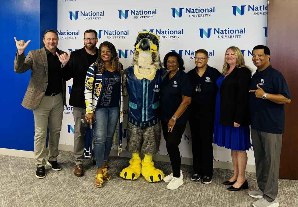 People posing with NU Mascot and doing "Wings Up" hand sign